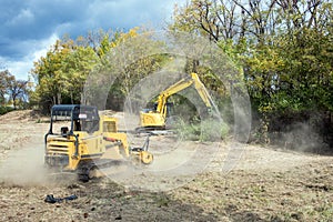 Mulcher and Backhoe Clearing Field with Stormy Sky