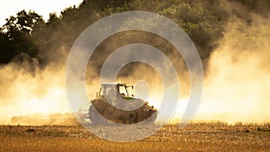 Mulching tractor after rapeseed harvest among the dust