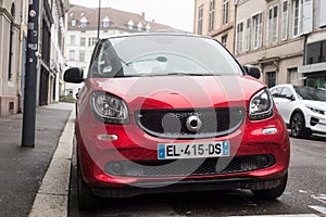 front view of red smart car parked in the street