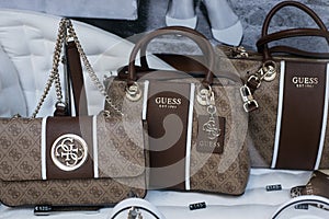 Brown leather hand bags collection by Guess in a luxury fashion store showroom