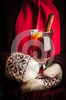 Mulled whine in the hands in knitted mittens vertical
