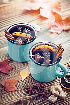 Mulled wine in blue enameled mugs with spices and citrus.