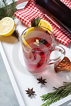 Mulled wine, a bottle of red wine, spruce branches, cinnamon, orange and lemon on white tray on concrete background. Winter drinks