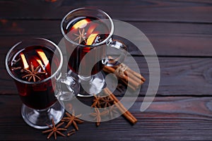 Mulled wine, cinnamon sticks and anise on dark wooden background