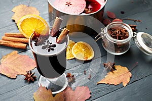 Mulled wine. Glass of winter hot drink with citrus, apple and spices. Stewpan with mulled wine and cinnamon sticks, slice of