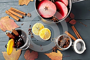 Mulled wine. Glass of winter hot drink with citrus, apple and spices. Stewpan with mulled wine and cinnamon sticks, slice of