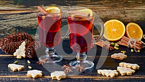 Mulled wine in the glasses with various winter spices on the black wooden background decorated with Christmas cookies