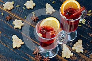 Mulled wine in the glasses with various winter spices - cinnamon, cardamom and anise on the black wooden background