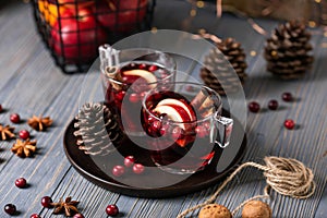 Mulled wine in glasses on a wooden background. Apples, cranberries, cinnamon, star anise.