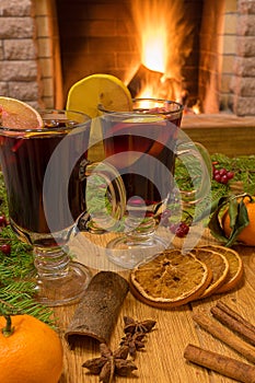 Mulled wine glintwine in drinking glasses and christmas decorations, against cozy fireplace background