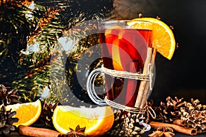 Mulled wine Hot christmas drink with spices on a dark christmas background. Orange slices, cinnamon sticks, christmas cones,