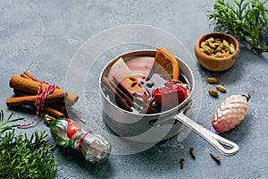 Mulled wine hot drink with citrus, apple, pomegranate and spices in aluminum casserole with vintage ÃÂ¡hristmas tree