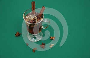 Mulled wine hot drink or tea with spices on a green background. Isolated. Traditional winter drink. Christmas concept, background,