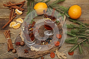 Mulled wine hot drink or tea with spices and spices on a wooden background with a branch of spruce. Traditional winter drink.