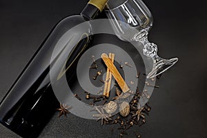 Mulled wine ingredients on a black background. Bottle of red wine Spices for hot alcoholic beverages, top view,