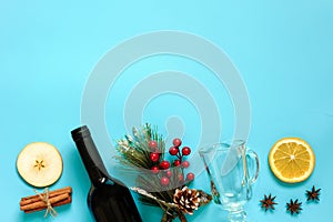 Mulled Wine Ingredients, still life on blue background. Bottle of wine, cinnamon sticks, slices of orange, apple, anise and mug.