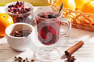 Mulled wine Karkade tea, with a badge and cardamom in a glass on a wooden table top orange