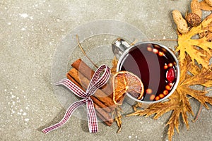 Mulled wine in metal rustic mug with spices and citrus fruits decorated with autumn leaves and pumpkin