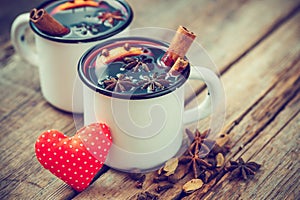 Mulled wine in mugs, red heart and spice on table.