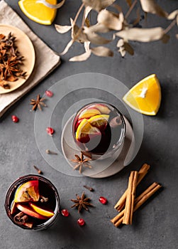 Mulled wine with orange, apple and cinnamon in glasses on a dark background. The concept of a traditional winter hot drink with
