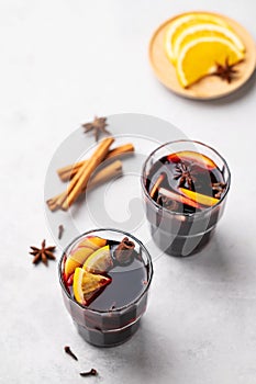 Mulled wine with orange, apple and cinnamon in glasses on a light background. The concept of a traditional winter hot drink with