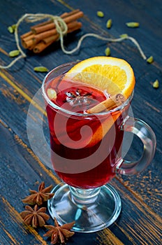 Mulled wine with orange slice and winter spices - cinnamon, cardamom and anise stars on the black wooden background