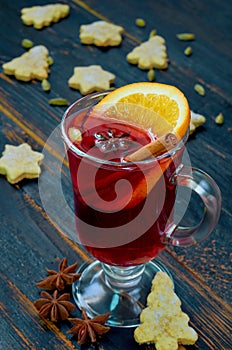 Mulled wine with orange slice and winter spices - cinnamon, cardamom and anise stars on the black wooden background
