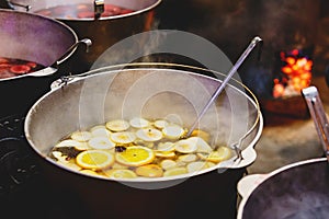 Mulled wine with oranges in large vats on Christmas market. New year and Christmas celebration concept, traditional drink