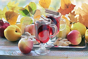 Mulled wine, organic fruits, autumn leaves, spices on a wooden table