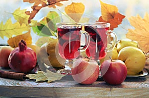 Mulled wine, organic fruits, autumn leaves, spices on a wooden table