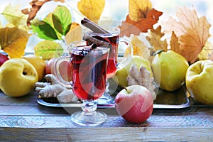 Mulled wine, organic fruits, autumn leaves, spices on a wooden table against the background of a window