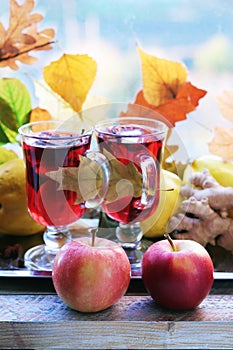 Mulled wine, organic fruits, autumn leaves, spices on a wooden table against the background of a window