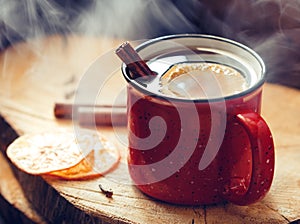 Mulled wine in a red ceramic mug over rustic wooden boards