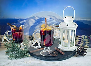 Mulled wine with spices and Christmas decoration on a wooden table against the background of a winter mountain