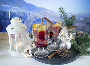 Mulled wine with spices and Christmas decoration on a wooden table against the background of a winter mountain