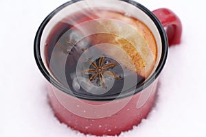 Mulled wine or tea on a snowy background during a snowfall in the forest. Winter hot drinks with aromatic spices of