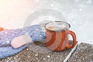 Mulled wine or tea on a wooden background during a snowfall in the forest. Winter hot drinks with aromatic spices of