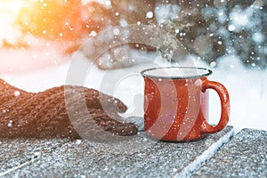 Mulled wine or tea on a wooden background during a snowfall in the forest. Winter hot drinks with aromatic spices of