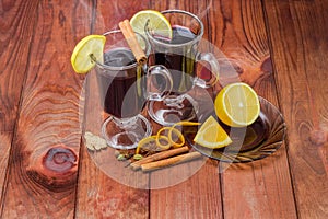 Mugs of mulled wine and mulling spices on wooden surface photo