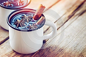 Mulled wine in white mugs with spices and citrus fruit.