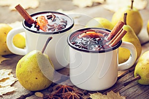 Mulled wine in white rustic mugs with spices and pear