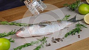 Mullet fish with marinade. Pepper the dish with pepper grinder