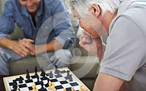 Mulling over his move. a father and son playing a game of chess together at home.