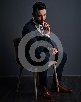 Mulling over his next business move. Studio shot of a stylish young businessman looking thoughtful against a gray