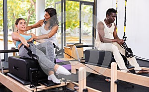 Multethnic group of people training pilates in gym with trainer