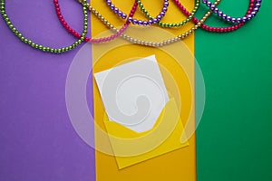 Multi color Mardi Gras beads and envelop with card on paper background. Top view