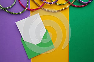 Multi color Mardi Gras beads and envelop with card on paper background. Top view