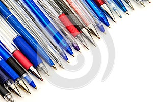 Multi-colored ballpoint pens on a white background, lots of blue ballpoint pens
