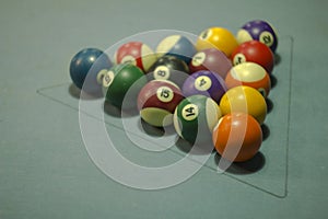 A multi-colored billiard balls with numbers on a blue cloth. balls in a triangle