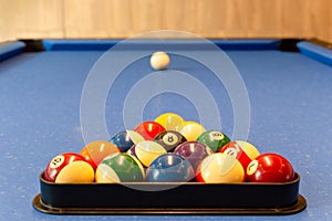 Multi colored billiard balls with numbers lie in a triangle pyramid on table.